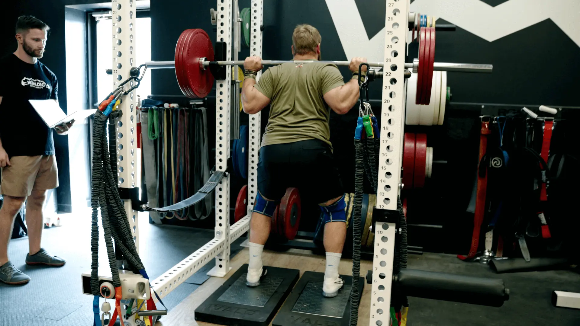 Wes setting up for his squat assessment on the ForceDecks, un-racking a weighted barbell from the squat rack.